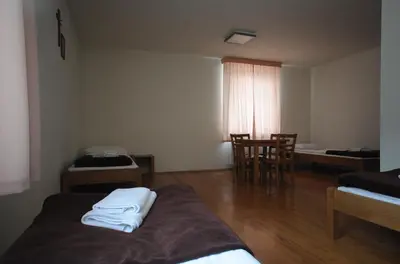 a room with two beds and a table and chairs at Dom Pielgrzyma KARMEL in Krzeszowice