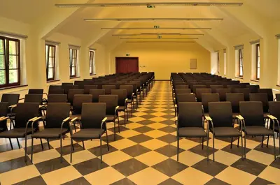 an empty hall with chairs and a checkered floor at Dom Pielgrzyma KARMEL in Krzeszowice