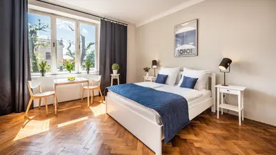 a white bedroom with a bed and a desk and a window at Fenna Apartments 7 minut od Rynku in Kraków