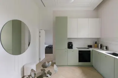 a kitchen with white cabinets and a round mirror at Wawel View I Koletek 17 in Kraków