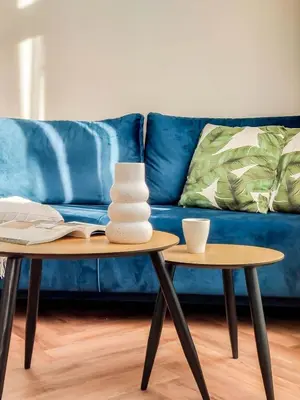 a living room with two tables and a blue couch at Meiselsa Apartments by Noah in Kraków