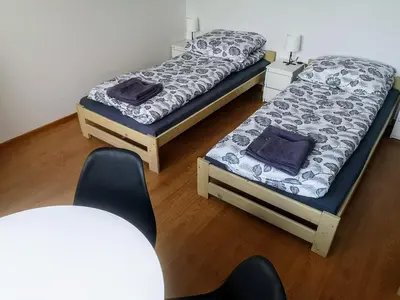 two twin beds in a room with a chair at Kwatery pracownicze Kęty Zielona in Kęty