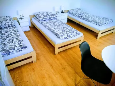 three beds in a room with a chair and a table at Kwatery pracownicze Kęty Zielona in Kęty