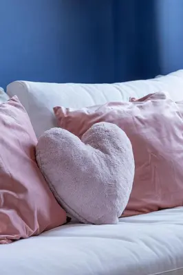 a heart stuffedanimal sitting on a bed with pillows at Uroczy Przestronny Apartament w Krakowie by Noclegi Renters in Kraków