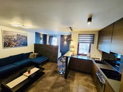 a living room with a blue couch and a kitchen at Apartament w centrum miasta, bezpłatny parking in Kraków