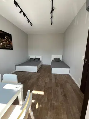 two beds in a white room with wooden floors at Płaszowska Apartment in Kraków