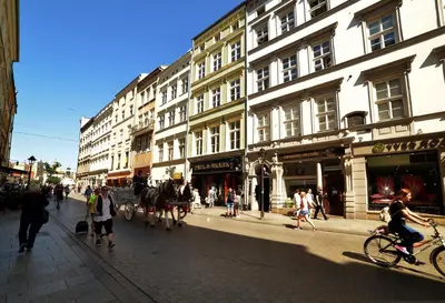 a city street with people walking and a horse drawn carriage at Grodzka Royal Apartments in Kraków
