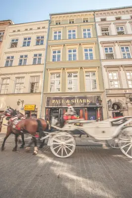 a horse drawn carriage in front of a building at Grodzka Royal Apartments in Kraków