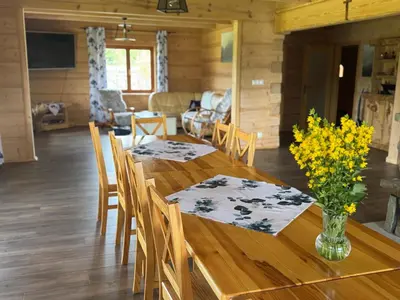 a dining room with a wooden table with flowers on it at Mecenasówka Noclegi in Zawoja