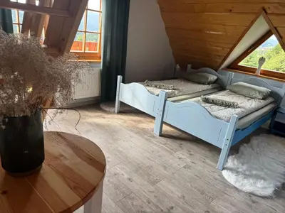 a bedroom with two beds and a table in a room at Mecenasówka Noclegi in Zawoja