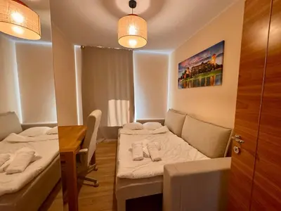 a small room with two beds and a table and a desk at Family Apartment Krakow Błonia in Kraków