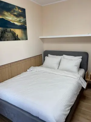 a bed with white sheets and a painting on the wall at Family Apartment Krakow Błonia in Kraków