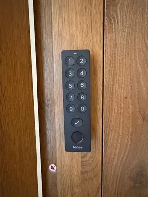 a black remote control on a wooden door at Family Apartment Krakow Błonia in Kraków