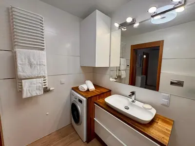 a bathroom with a washing machine and a sink at Family Apartment Krakow Błonia in Kraków