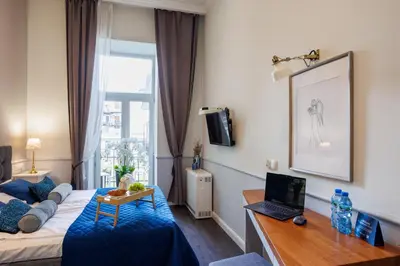 a hotel room with a bed and a desk with a laptop at Malila Premium Aparthotel Sebastiana 20 Old Town in Kraków