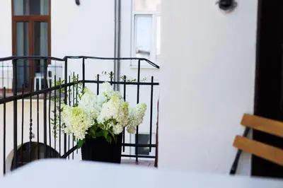 a vase of white flowers sitting on a balcony at Malila Premium Aparthotel Sebastiana 20 Old Town in Kraków