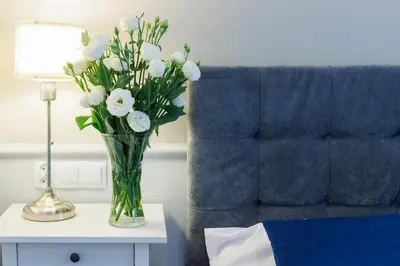 a vase of white flowers on a table next to a couch at Malila Premium Aparthotel Sebastiana 20 Old Town in Kraków