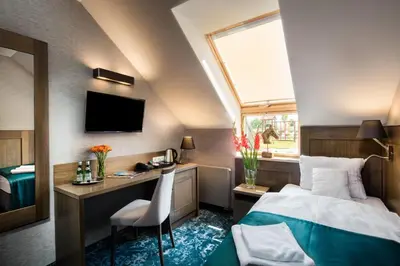 a bedroom with a bed and a desk and a tv at Hotel Szary Residence in Michałowice