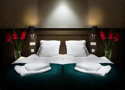 a large bed with white pillows and red flowers at Hotel Szary Residence in Michałowice