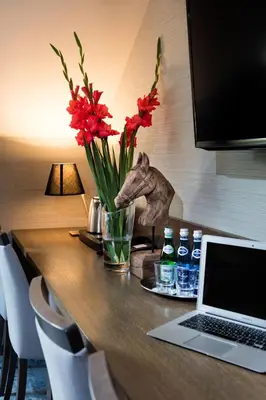 a desk with a laptop and flowers and bottles of water at Hotel Szary Residence in Michałowice