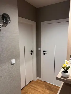 a room with two white doors and a vase of flowers at Apartament Dominikanów 28m36 in Kraków