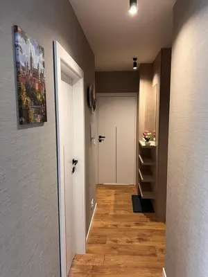 a hallway with a white door and wooden floors at Apartament Dominikanów 28m36 in Kraków