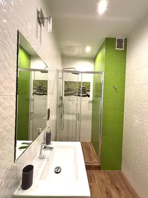 a bathroom with a sink and a shower with a mirror at Przytulne mieszkania na wynajem in Kraków