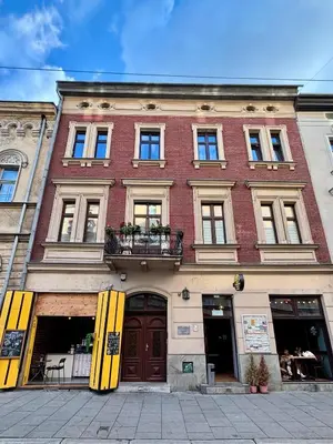 a large red brick building with yellow doors and windows at Przytulne mieszkania na wynajem in Kraków