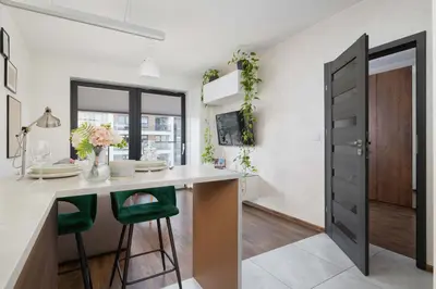 a kitchen with a counter and stools at a table at Light Grey Apartment in Cracow with Furnished Balcony by Noclegi Renters in Kraków