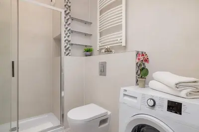 a bathroom with a washing machine and a shower at Light Grey Apartment in Cracow with Furnished Balcony by Noclegi Renters in Kraków