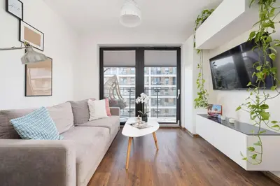 a living room with a couch and a table at Light Grey Apartment in Cracow with Furnished Balcony by Noclegi Renters in Kraków