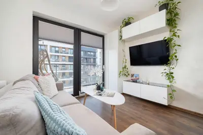 a living room with a couch and a tv at Light Grey Apartment in Cracow with Furnished Balcony by Noclegi Renters in Kraków