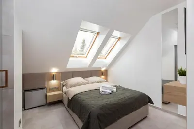 a bedroom with a bed and two windows at Volare Balice in Cholerzyn