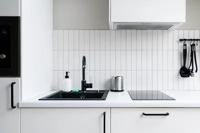 a kitchen with a black sink and white tiles at Charming designer attic in Kraków