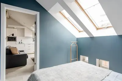 a bedroom with blue walls and a bed and a couch at Charming designer attic in Kraków
