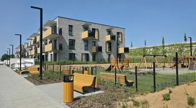 a playground with benches and swings in front of a building at Podłęże Trawniki Industrial Zone