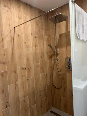 a shower in a bathroom with a wooden wall at 4 Żywioły-Noclegi w Beskidach basen sauna jacuzzi in Koziniec