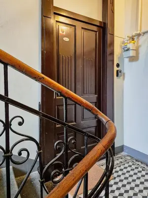 a wooden door in a building with a black railing at Old Town PLAC SZCZEPAŃSKI Premium Apartments in Kraków