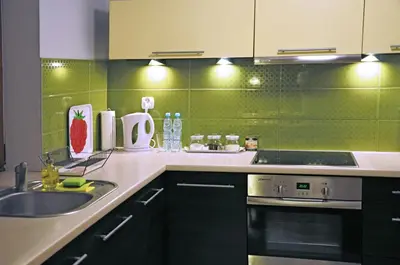 a kitchen with green tile on the wall and a sink at Color Apartment in Kraków