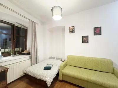 a living room with a green couch and a window at Cozy Asnyka in Kraków