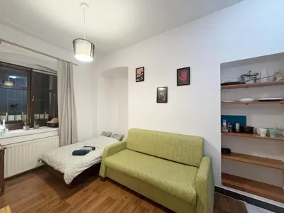 a living room with a green couch and a window at Cozy Asnyka in Kraków