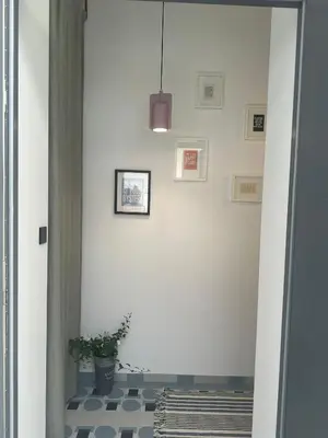 a hallway with a potted plant and a white wall at Green Harmony Apartment in Kraków