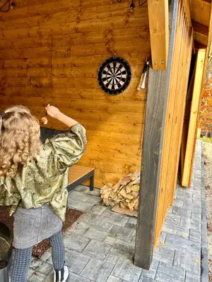 a woman standing in front of a log cabin at Gorczańska Przystań in Zasadne