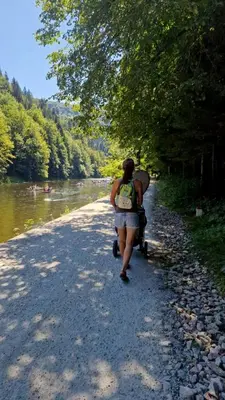 a woman walking down a path next to a river at Gorczańska Przystań in Zasadne