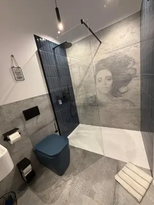 a bathroom with a shower with a blue toilet at Blue Harmony Apartment in Kraków
