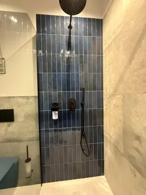 a shower in a bathroom with a blue tiled wall at Blue Harmony Apartment in Kraków