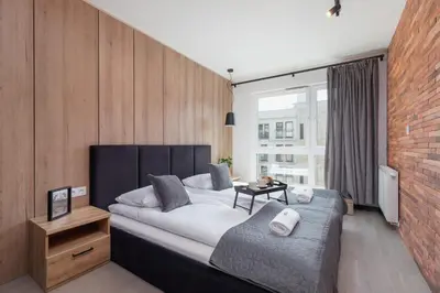 a bedroom with a large bed and a brick wall at Elegant & Bright Apartment Zabłocie by Renters Prestige in Kraków