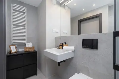 a bathroom with a sink and a tv on the wall at Elegant & Bright Apartment Zabłocie by Renters Prestige in Kraków