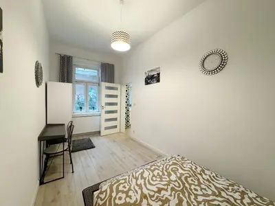 a bedroom with a bed and a desk and a window at White & Black - near Wawel Castle in Kraków