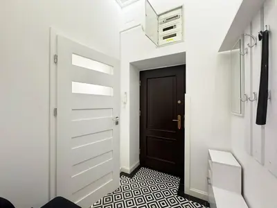 a hallway with a black door and a tile floor at White & Black - near Wawel Castle in Kraków